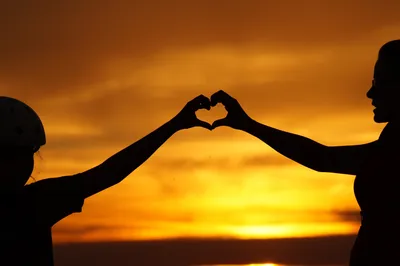 Child making heart silhouette in the sun